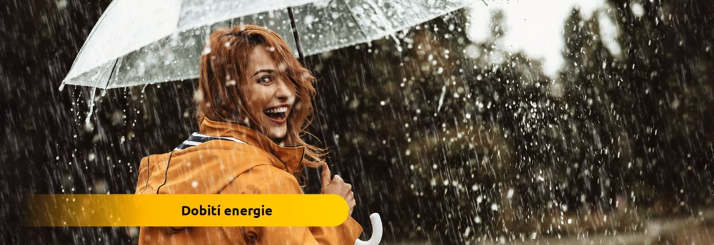 Aktivní usmívající se žena v dešti s deštníkem